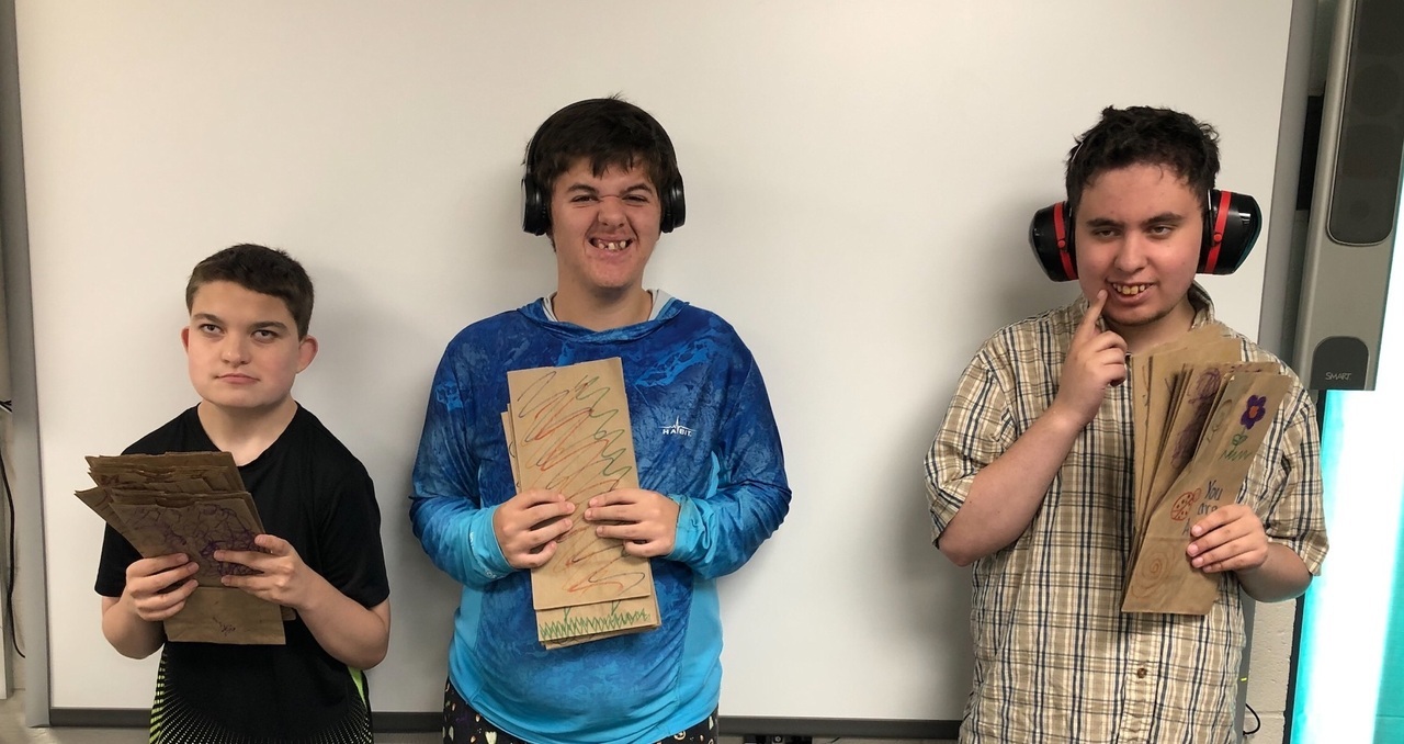 3 boys with special needs holding lunch bags they decorated