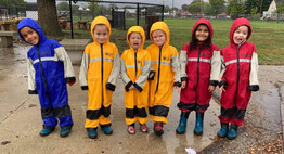 preschool students playing outside in the rain in rain gear