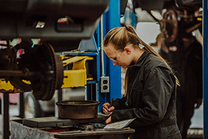 female student working on tire of car