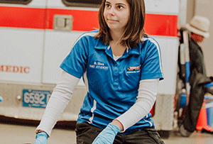 female student poses in front of an ambulance