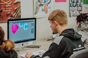 male graphic design student uses computer to design logo