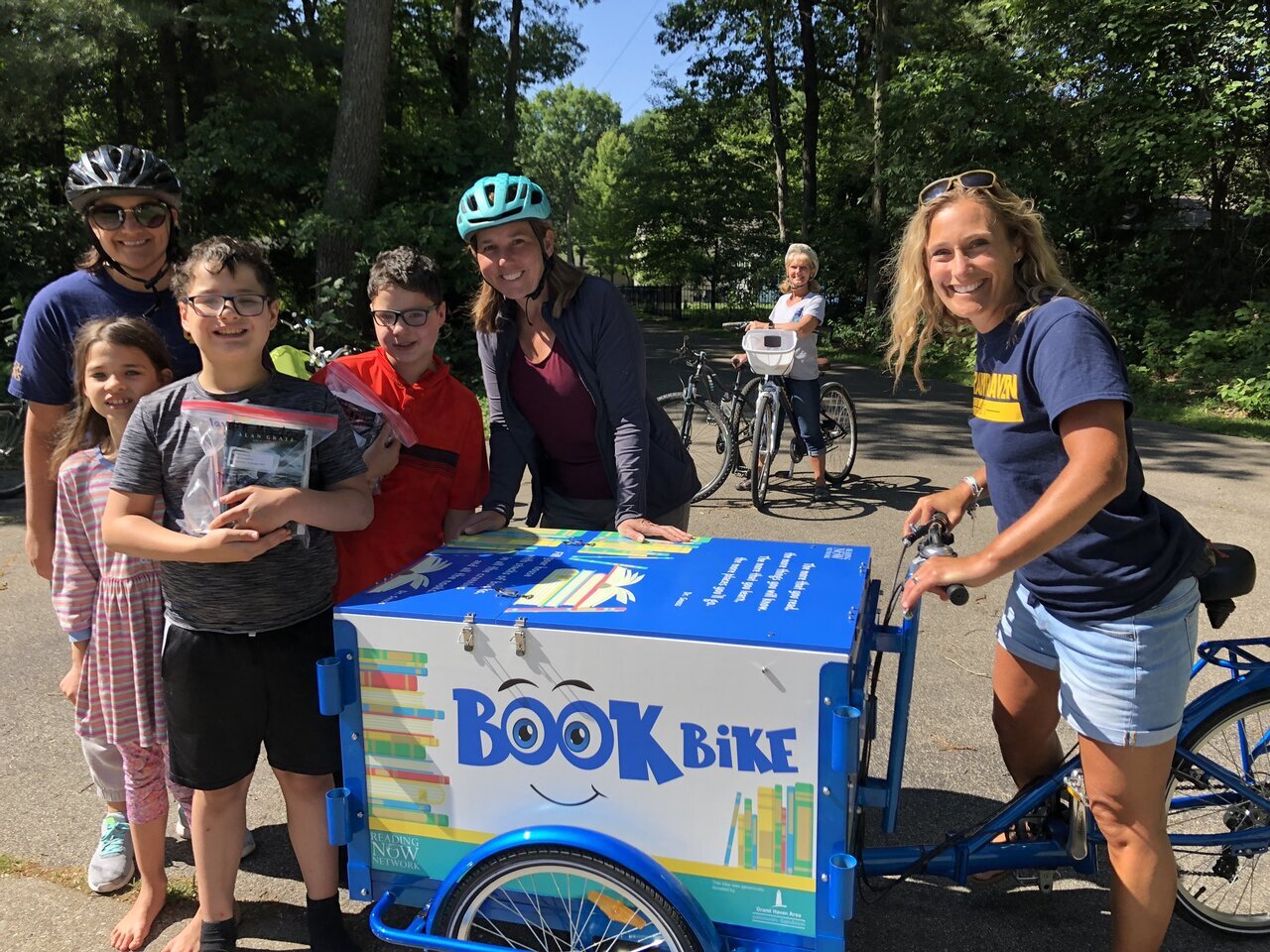 teacher riding the book bike with students and their new books